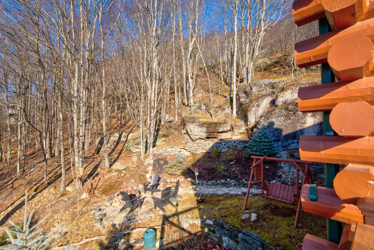 An outdoor seating area around a fire pit, surrounded by trees and a stone path. The atmosphere suggests cozy evenings spent stargazing, sipping hot cocoa, or sharing stories by the fire—perfect for family bonding after a day of mountain activities.