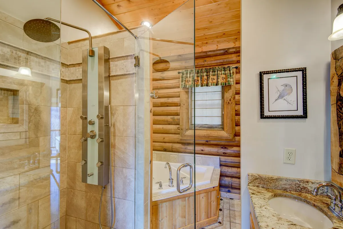A luxurious bathroom showcasing a modern shower with sleek fixtures, a jacuzzi tub, natural wood accents, and a granite countertop. The space exudes tranquility and offers a spa-like experience for guests.