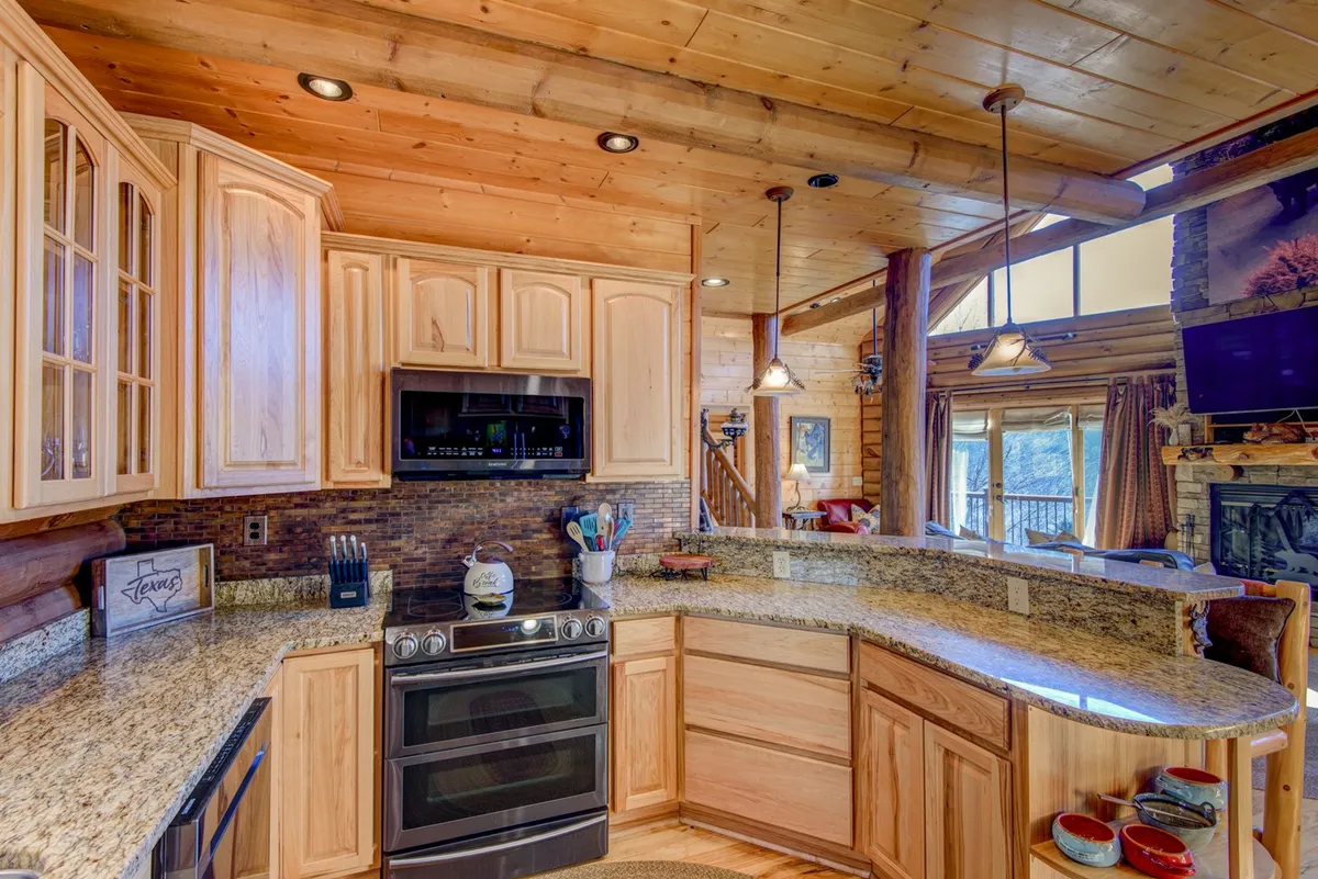 A view of the well-equipped kitchen, featuring granite countertops, wood cabinetry, and modern appliances in an open layout. The space is designed to welcome cooks and company alike, with plenty of room for culinary adventures and shared laughter.