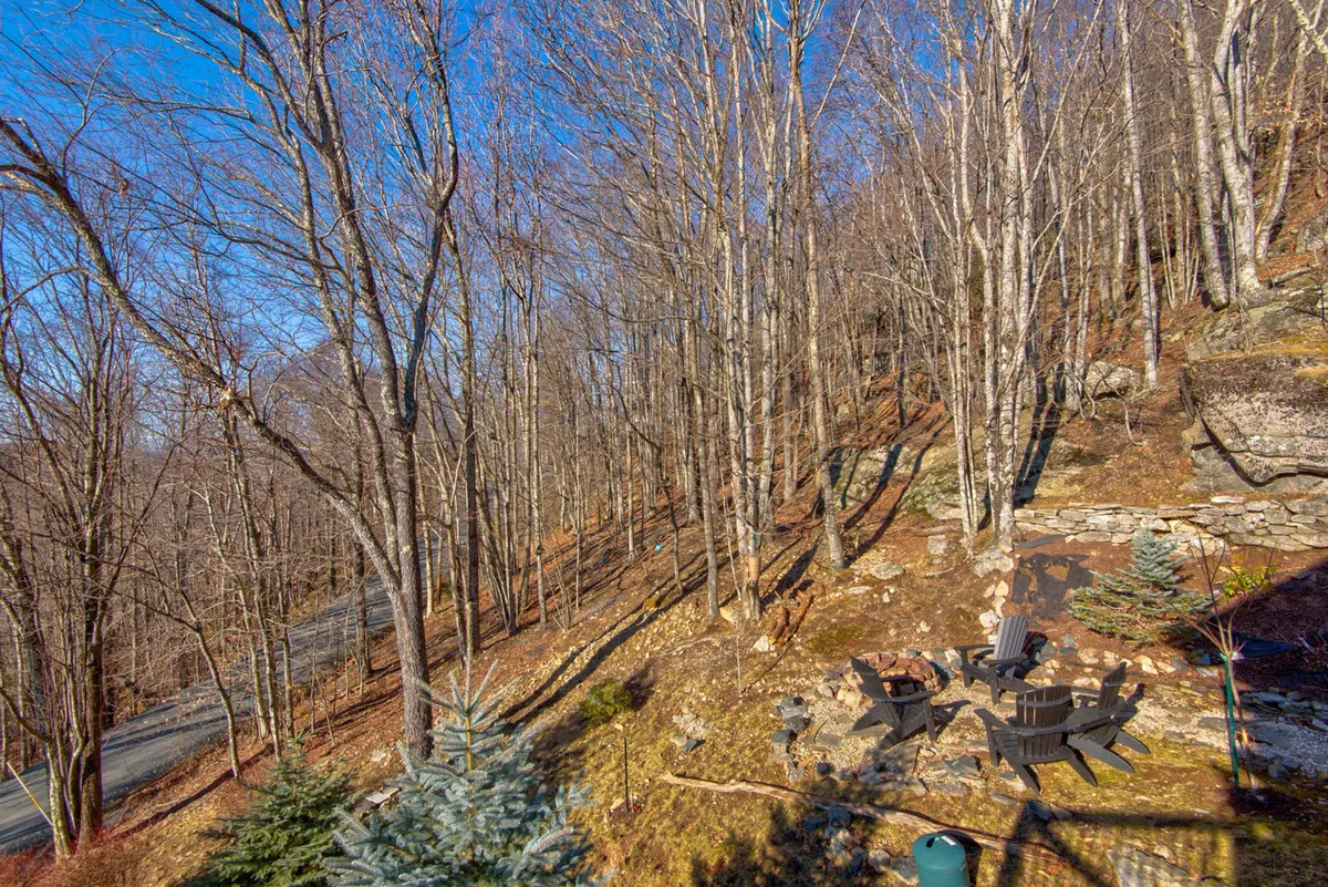 A rustic fire pit surrounded by wooden chairs sits amidst rocky terrain and bare trees, suggesting both communal gatherings and peaceful solitude in nature. The setting feels welcoming for evening storytelling or stargazing after a day of exploring.